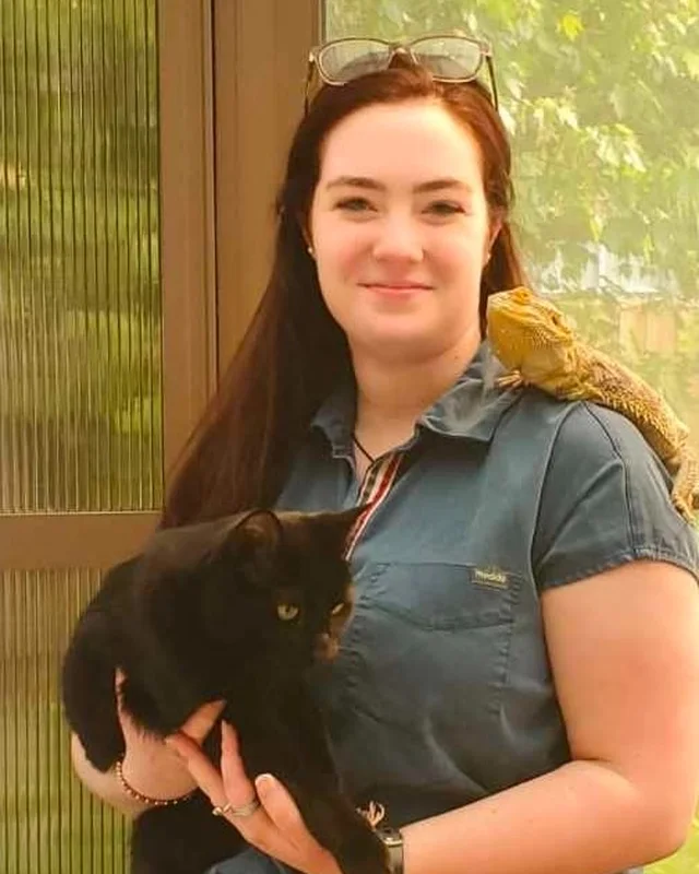 Darrah holding a black cat, with a bearded dragon on her shoulder